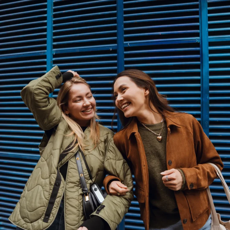 Zwei Frauen vor blauer Wand.